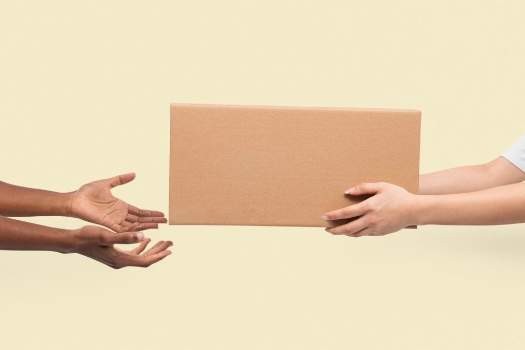 braços de uma mulher entregam caixa para outros braços femininos